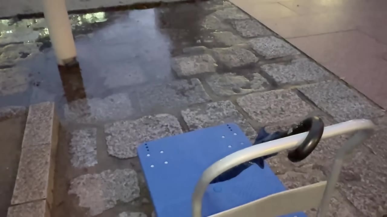 雨の中、台車で荷物を運ぶ