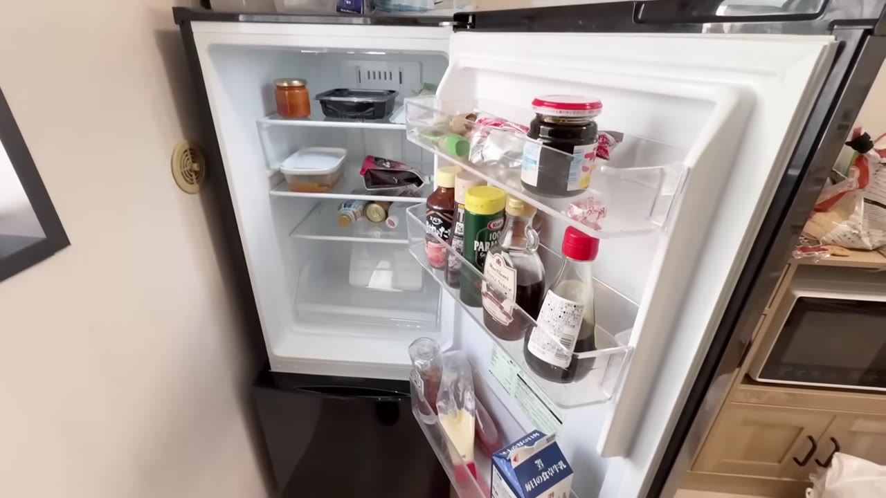 開けた冷蔵庫。棚はほぼ空で、扉に調味料が並ぶだけ